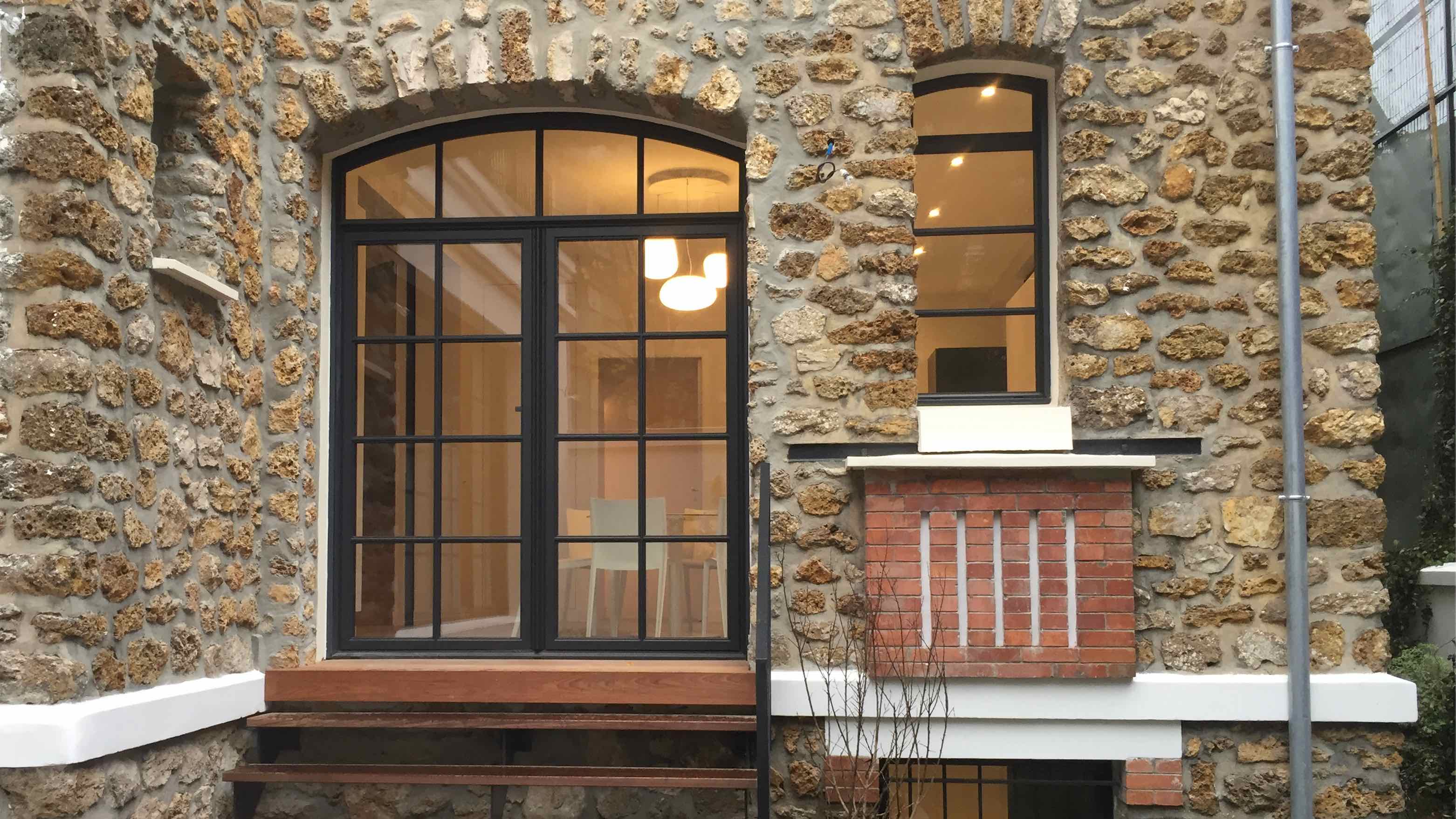 Maison en pierre avec fenêtres et porte à l'aspect acier.